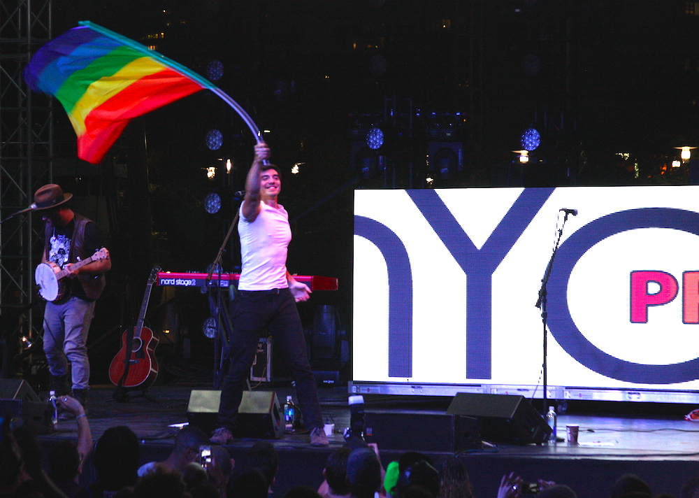 Steve Grand works the stage with a massive rainbow flag ©MRNY